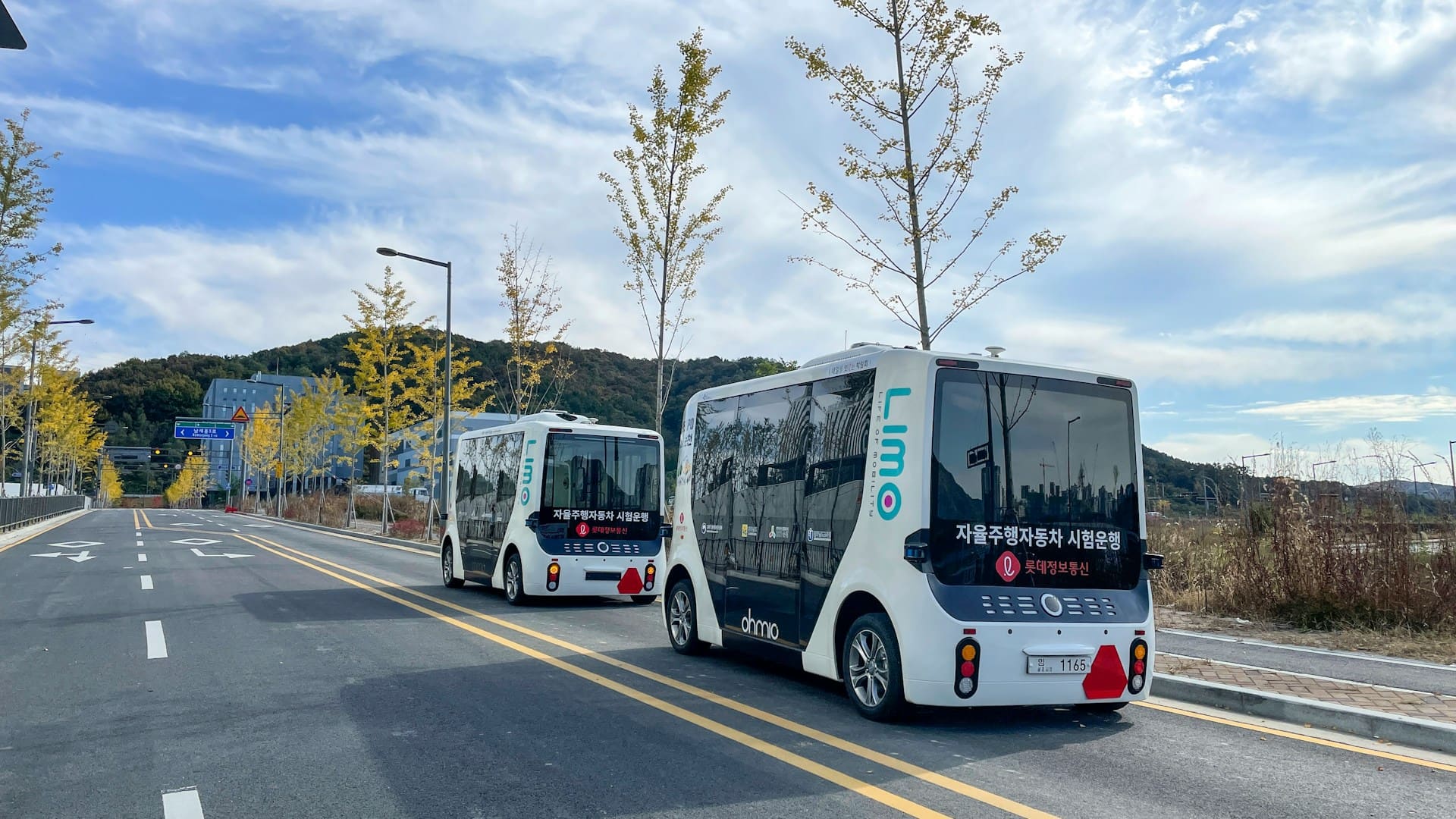 Two autonomous electric shuttles traveling on an urban road, illustrating smart transportation and autonomous mobility.